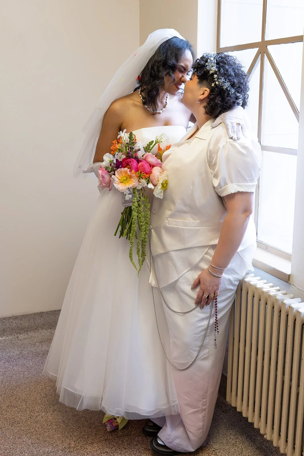 Bride and groom sharing a quiet, affectionate moment together by a window on their wedding day.