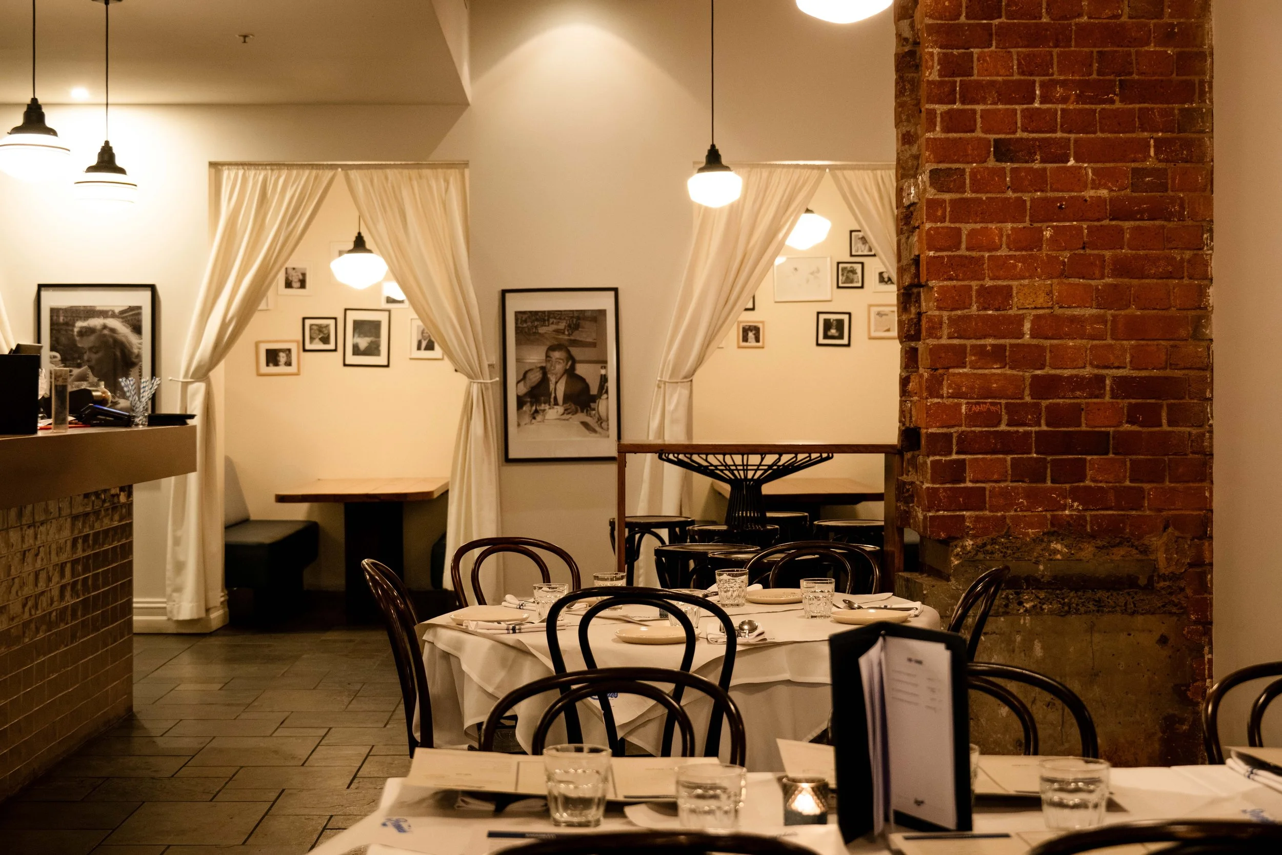 The Back Bar at Ronnie’s, with curtained booths, framed photographs and bistro chairs