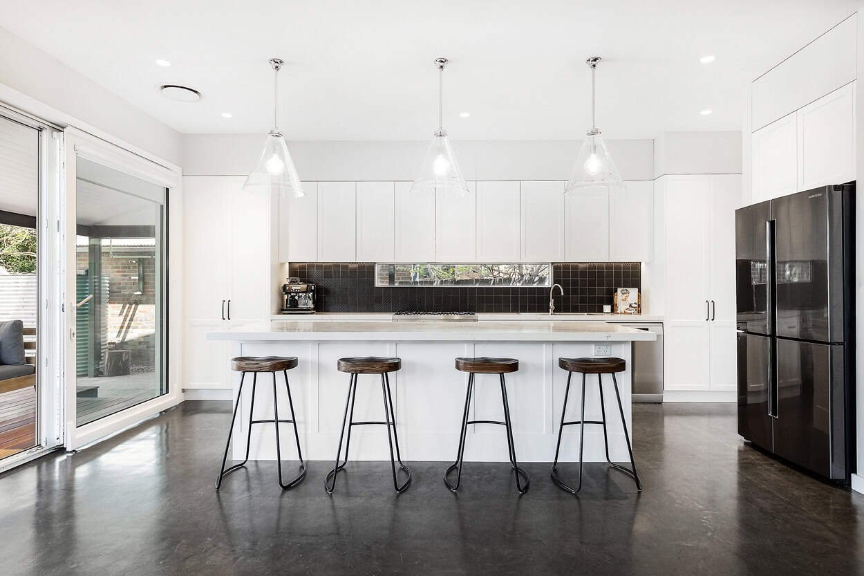 Modern kitchen with a large island, four bar stools, pendant lights, and stainless steel appliances.