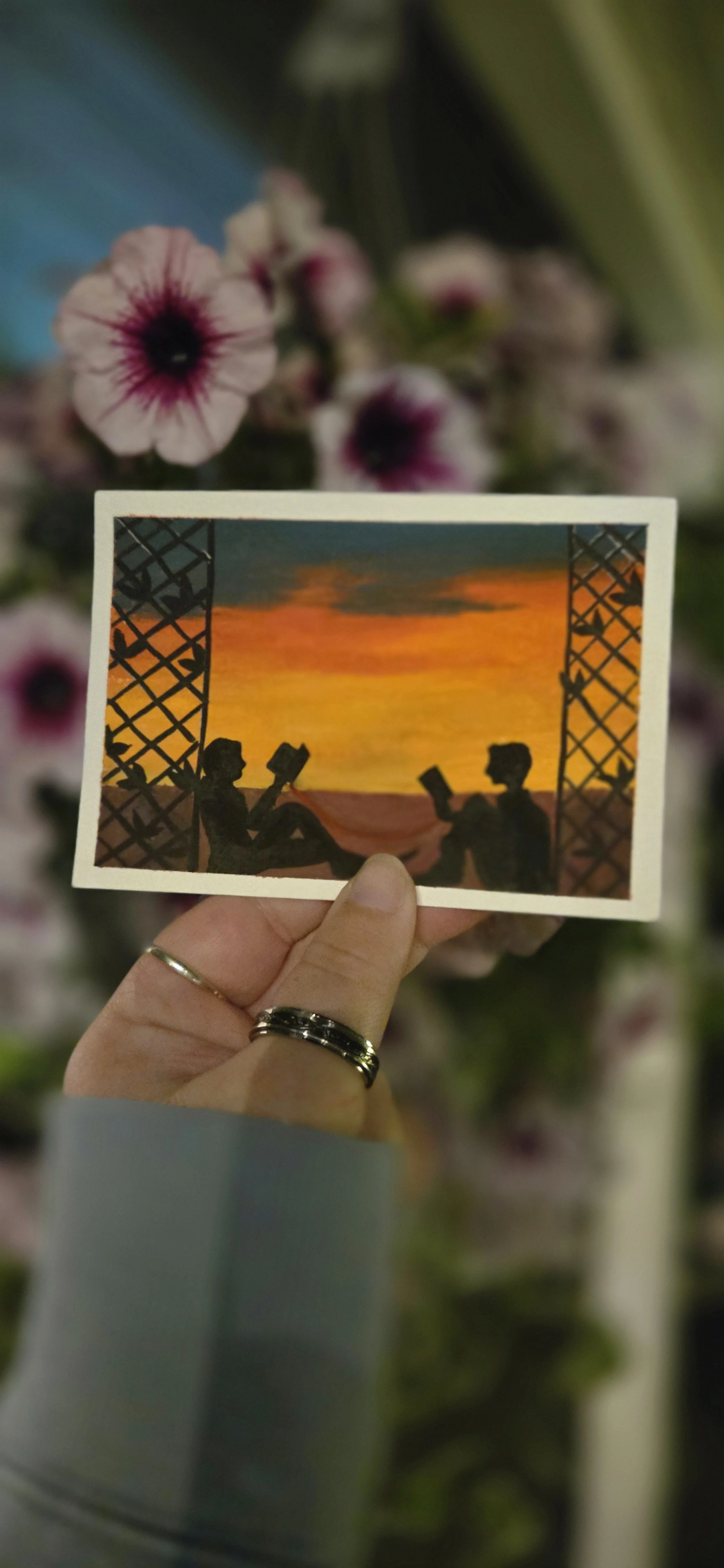 Silhouette of two people reading books against a sunset sky, framed by a porch with lattice sides.