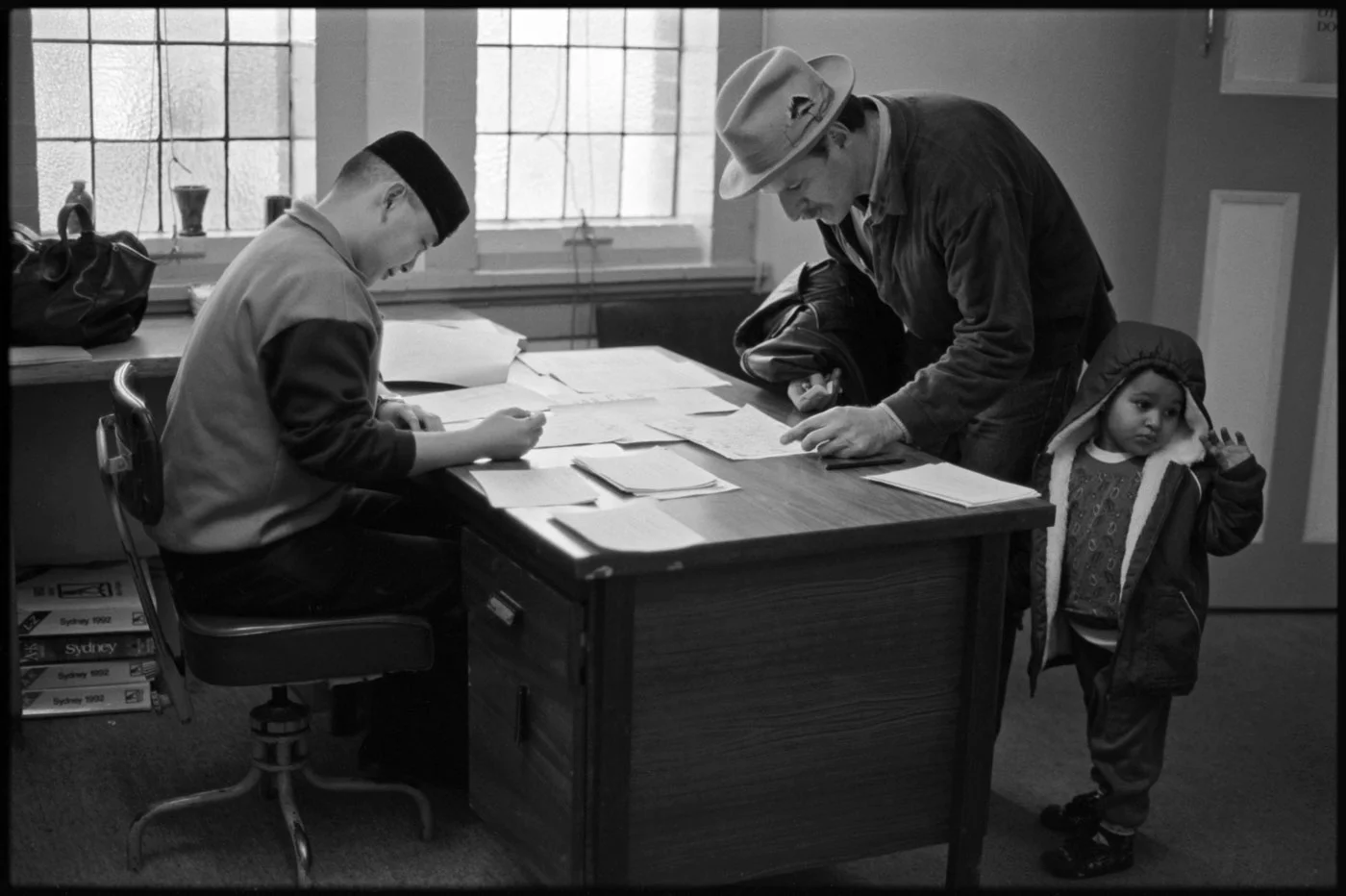 Staff assistant Stephen Law seated and stallholder Ray James and his daughter | 1992 | R26-16