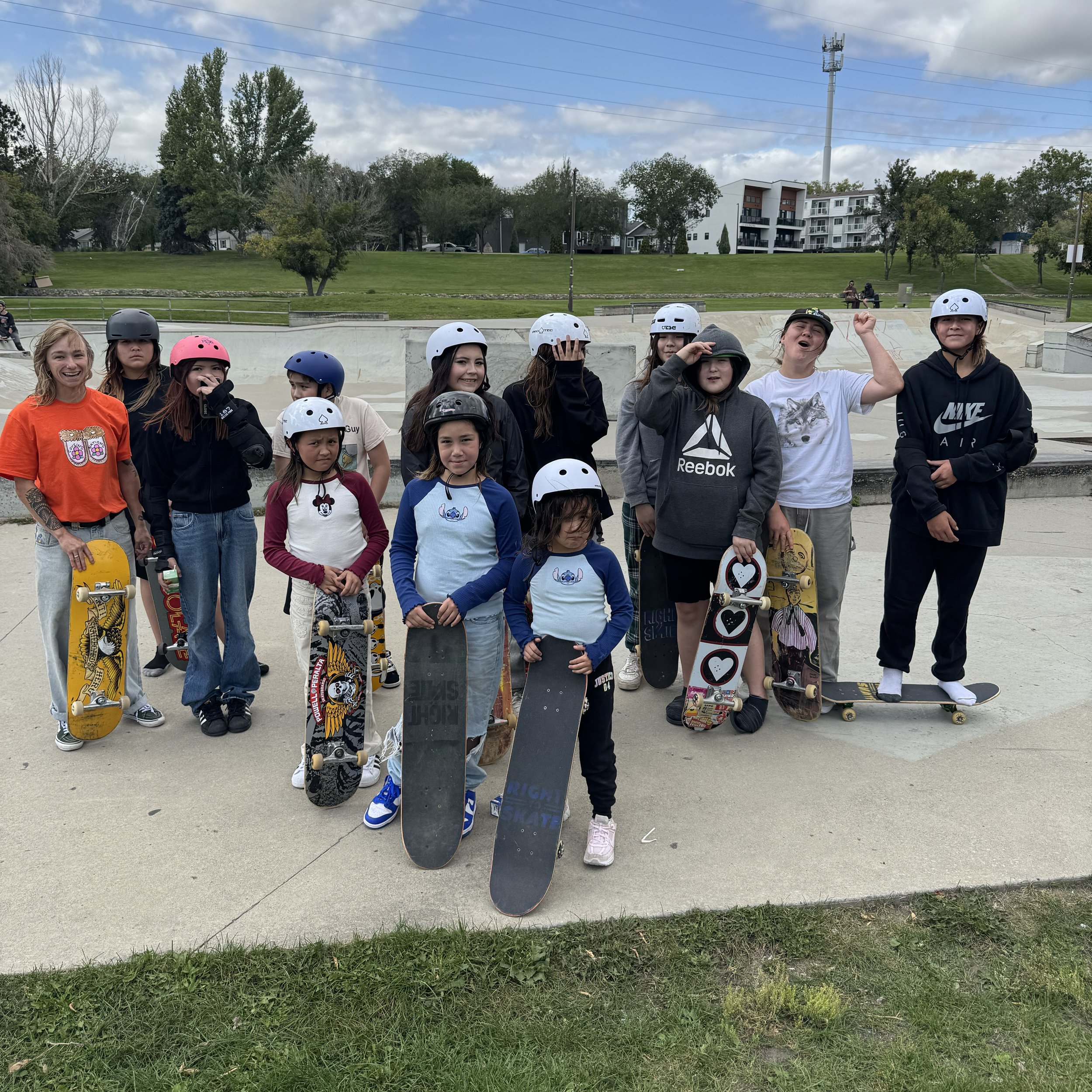 Group of children in a Right To Skate class at skate park, some holding skateboards and wearing helmets, posing for a photo.