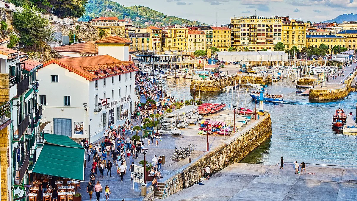 Crowded harbor in San Sebastian, Spain with boats and historic architecture.