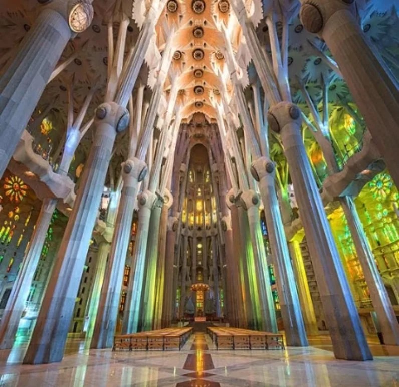 Interior of Sagrada Familia with colorful stained glass windows and ornate columns.