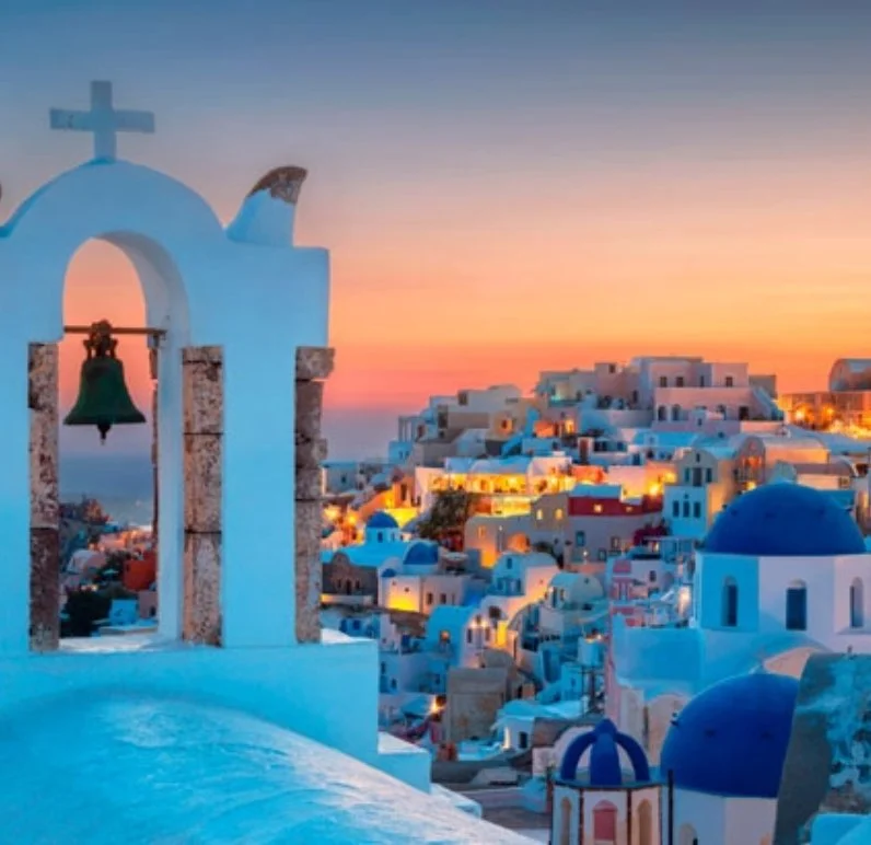 Scenic view of Santorini, Greece with white buildings and blue domes at sunset.