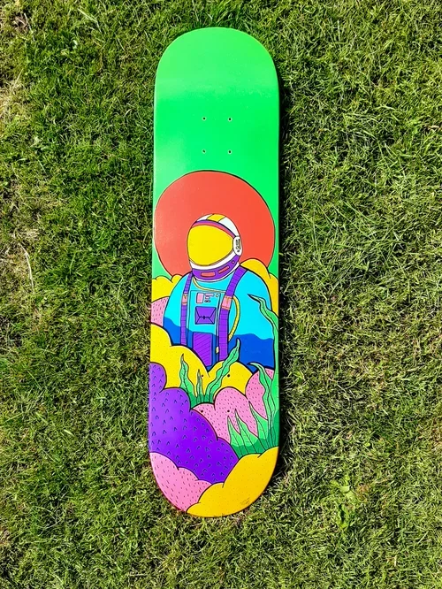 Colorful skateboard with an illustration of an astronaut in space suit surrounded by vibrant plants, on green grass.