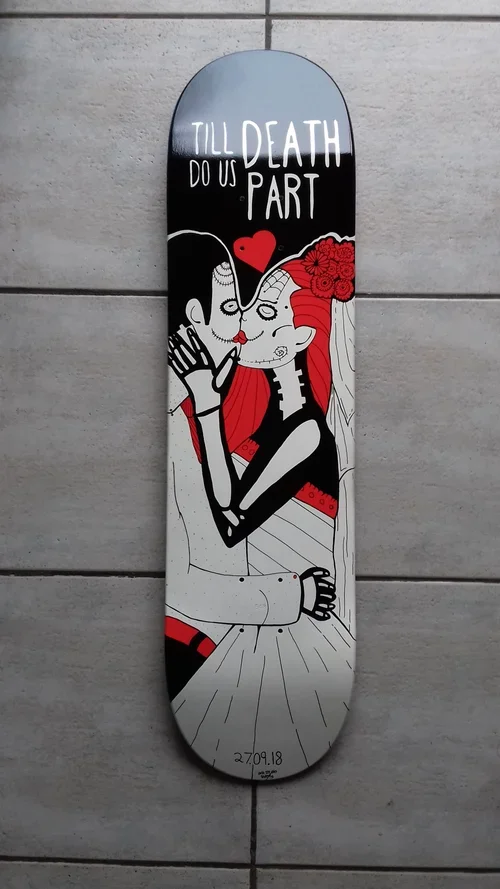A skateboard deck with a graphic of a skeleton man and a woman with red hair, embracing and whispering to each other with a red heart between them. The top of the deck has the text 'TILL DEATH DO US PART' in white letters.