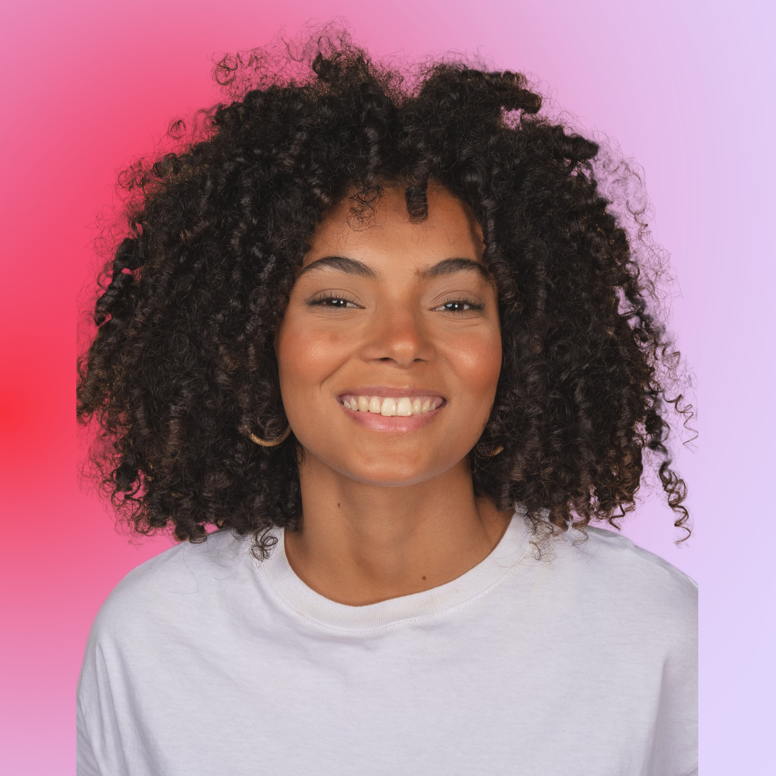 A woman with a big curly afro, wearing a white t-shirt, smiling against a pink and purple gradient background.