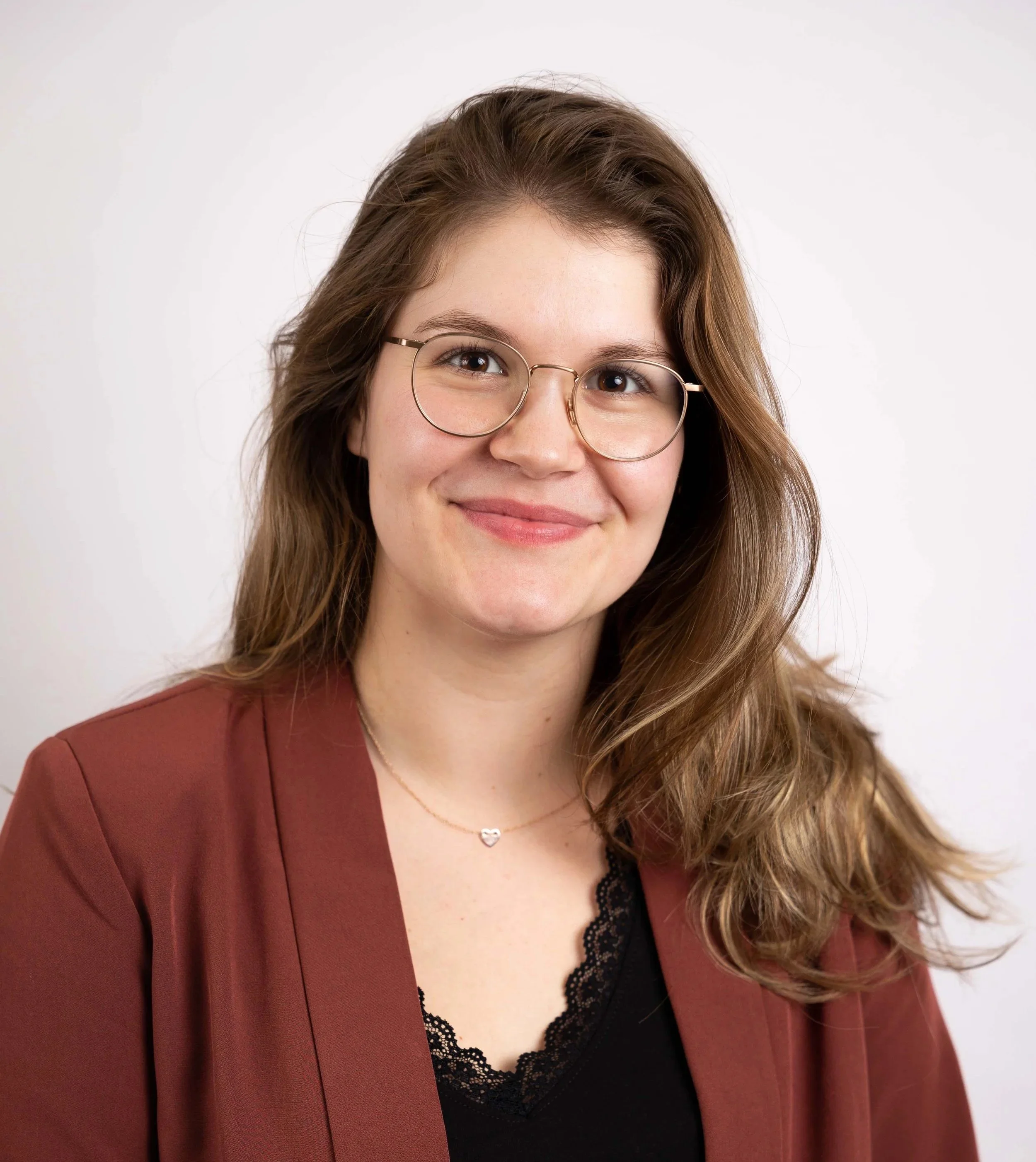 Frau mit Brille und rotem Shirt, wirkt selbstbewusst und ruhig.