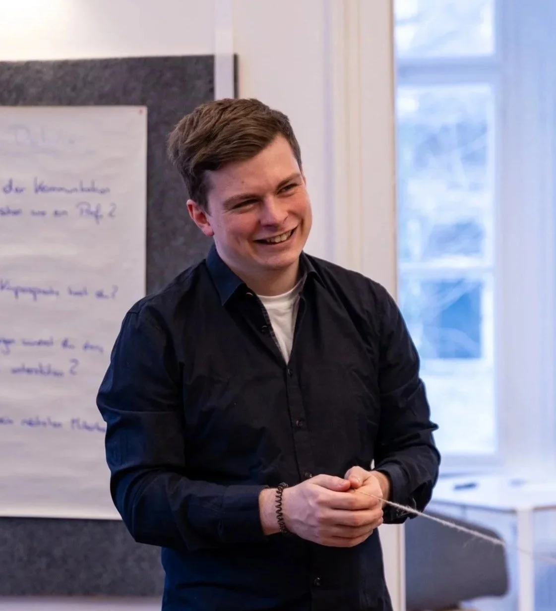 Mann mit weißen Hemd und verschränkten Armen, wirkt sympathisch und offen