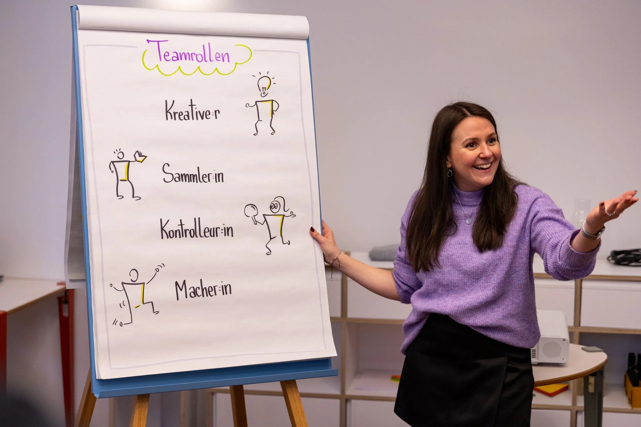 Lächelnde, mittelalte Frau mit dunkelbraunen Haaren und goldener Halskette.
