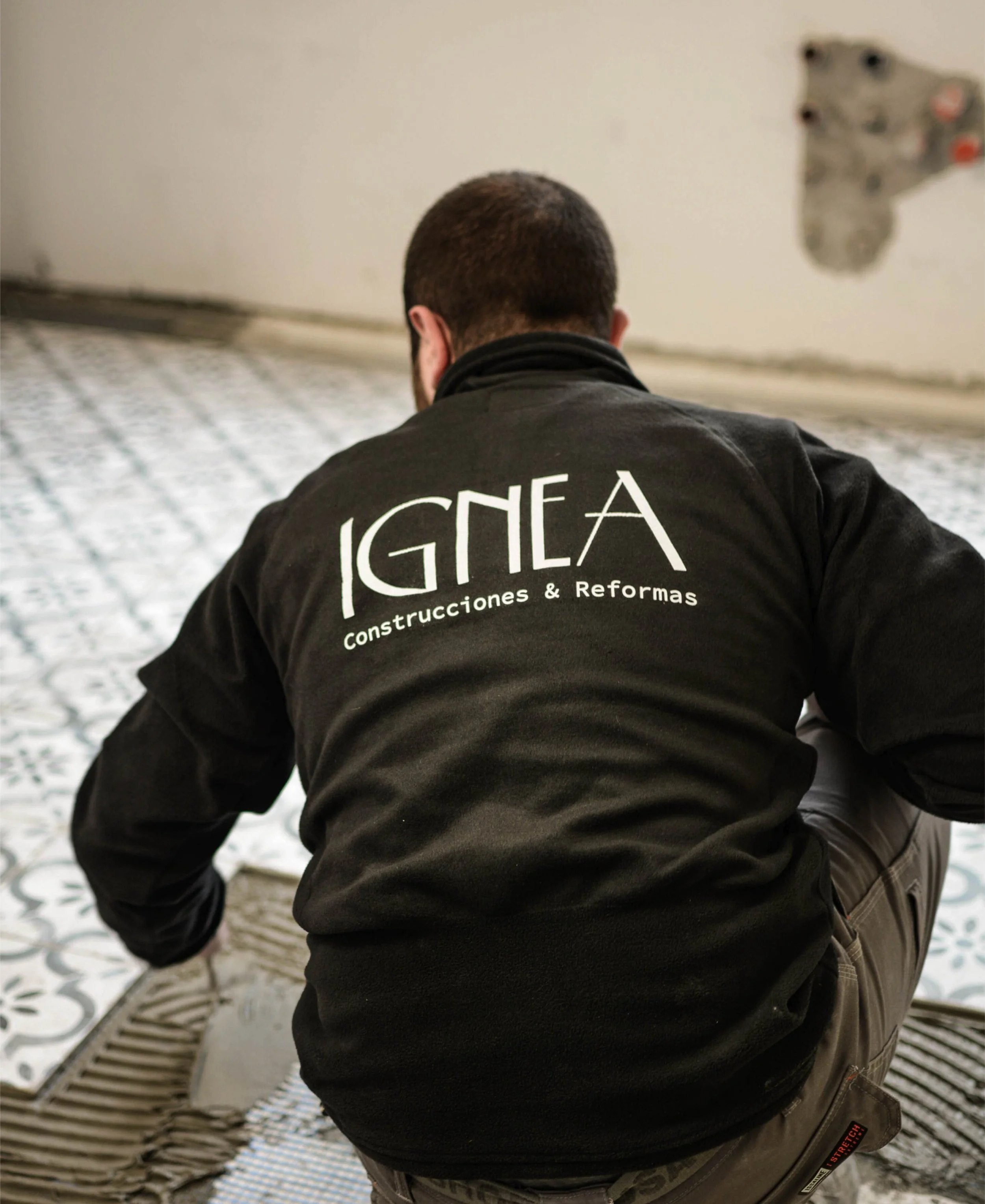 Trabajador de construcción instalando azulejos en un suelo interior. Diseño de Logotipo para una empresa de construcción por GustoStudio en Asturias.