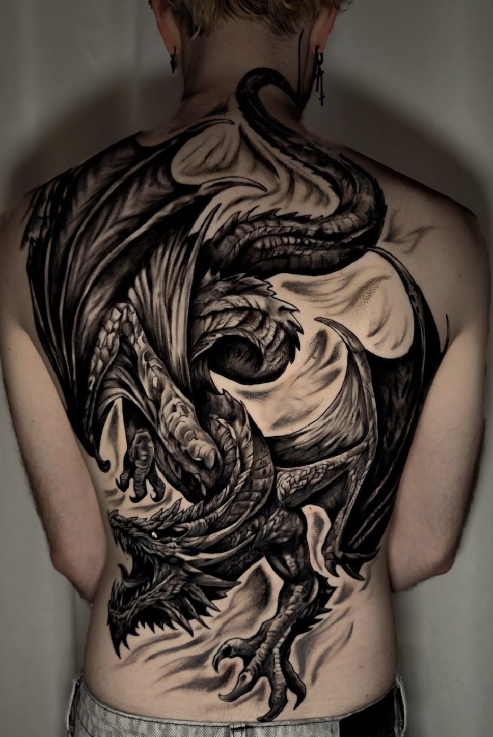Grand tatouage de dos avec un dragon dark realism en noir et gris réalisé à Bienne par André Dutoit.