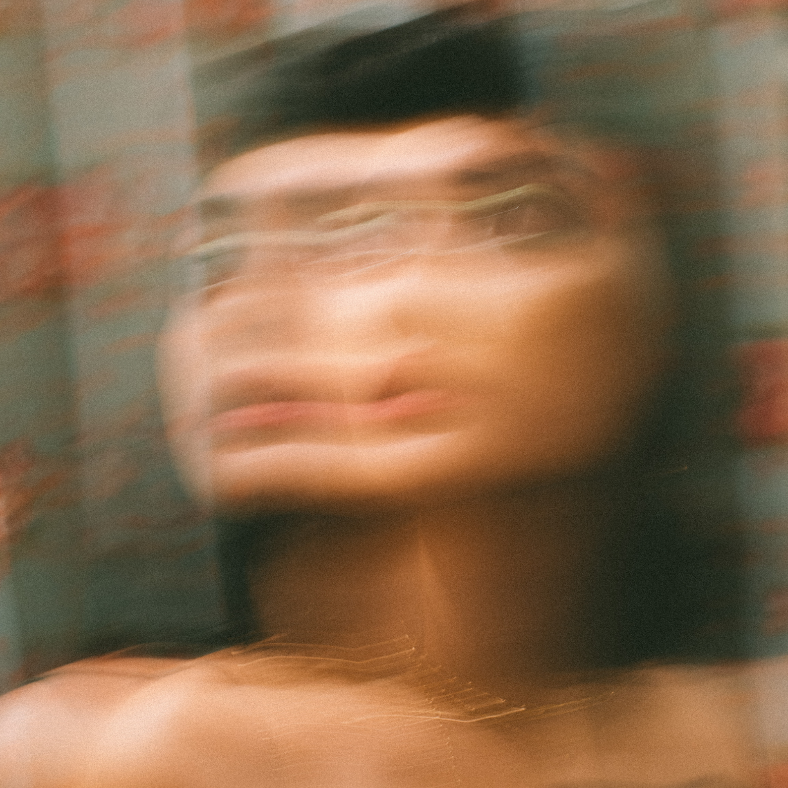 Blurred portrait of a person with a distorted face and soft colors.