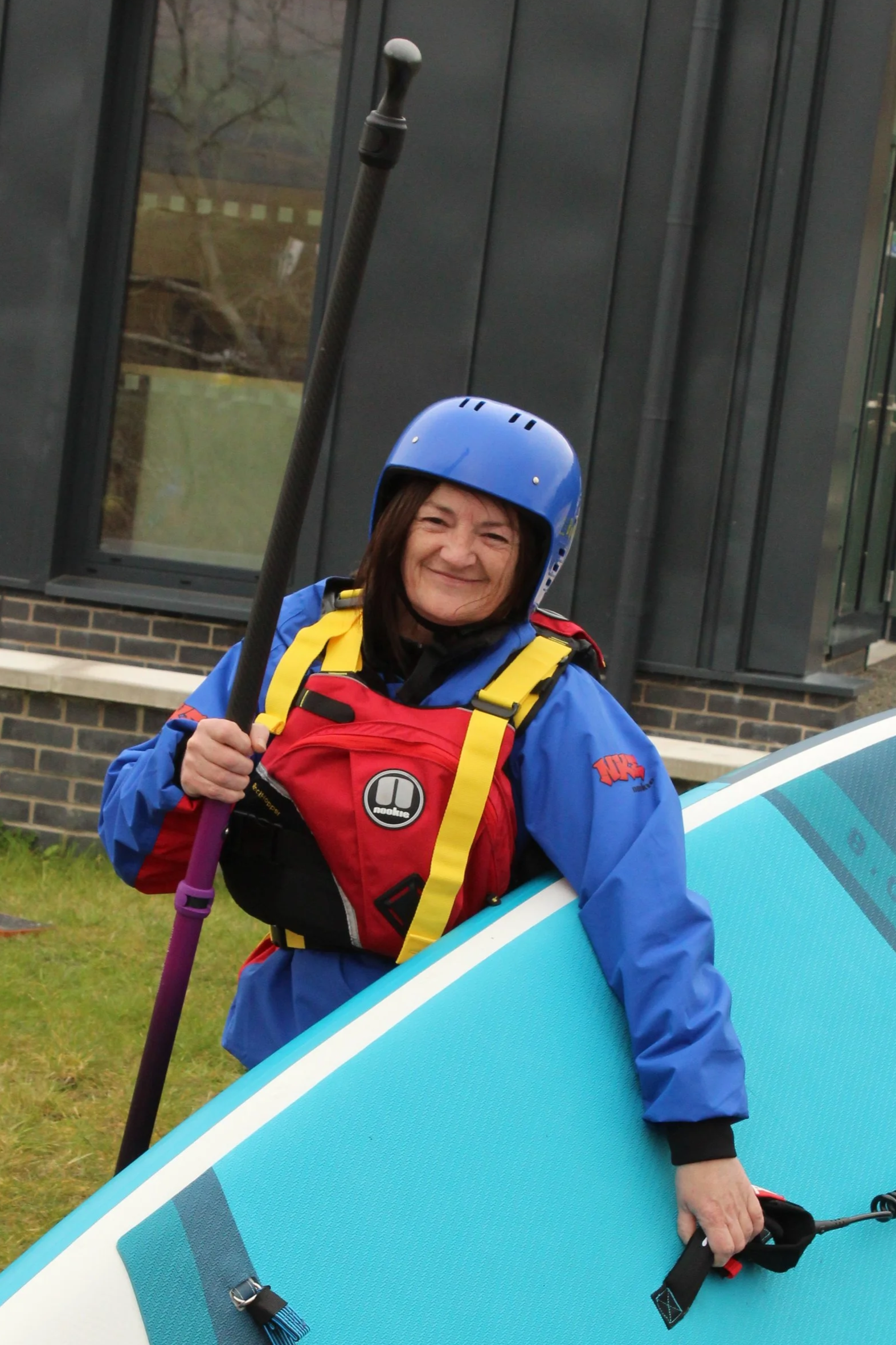 A woman and a young girl planting a seedling in a garden bed outdoors on a sunny day.