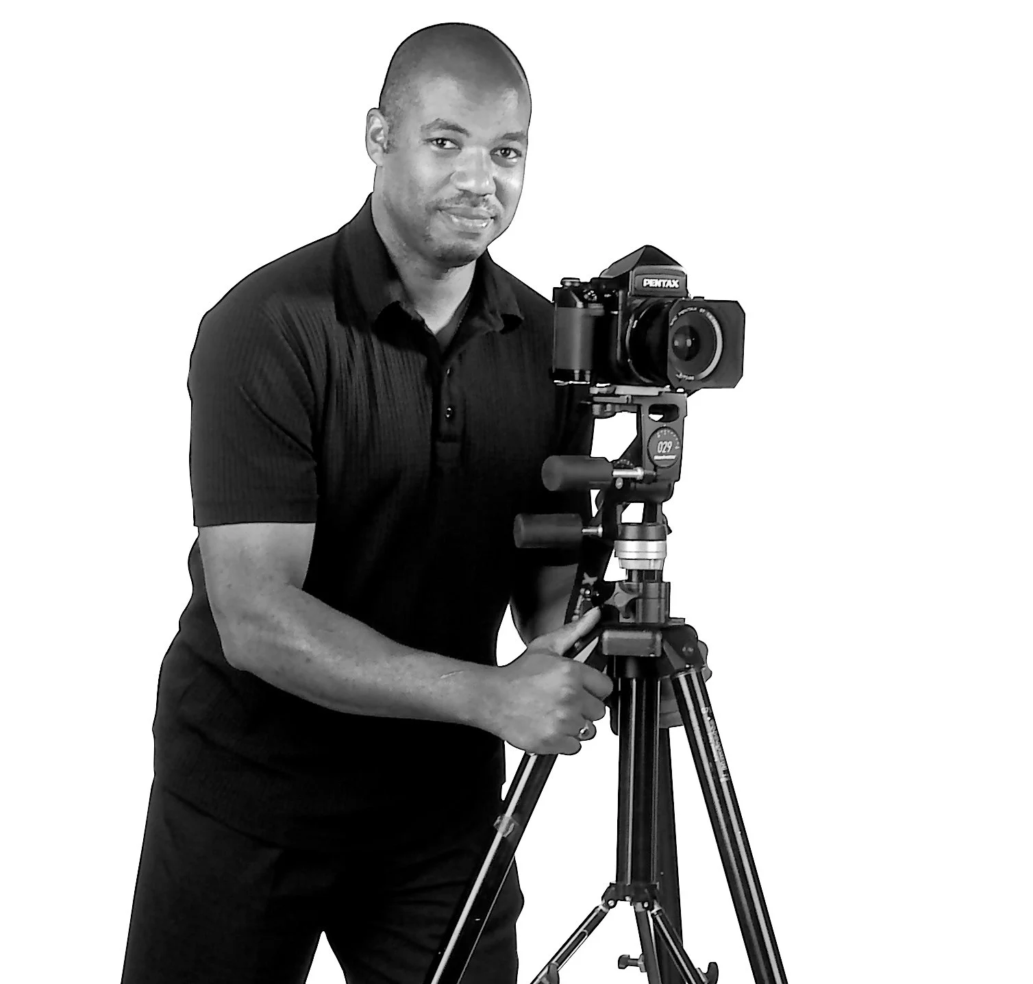 A man in a black shirt adjusting a professional camera mounted on a tripod.