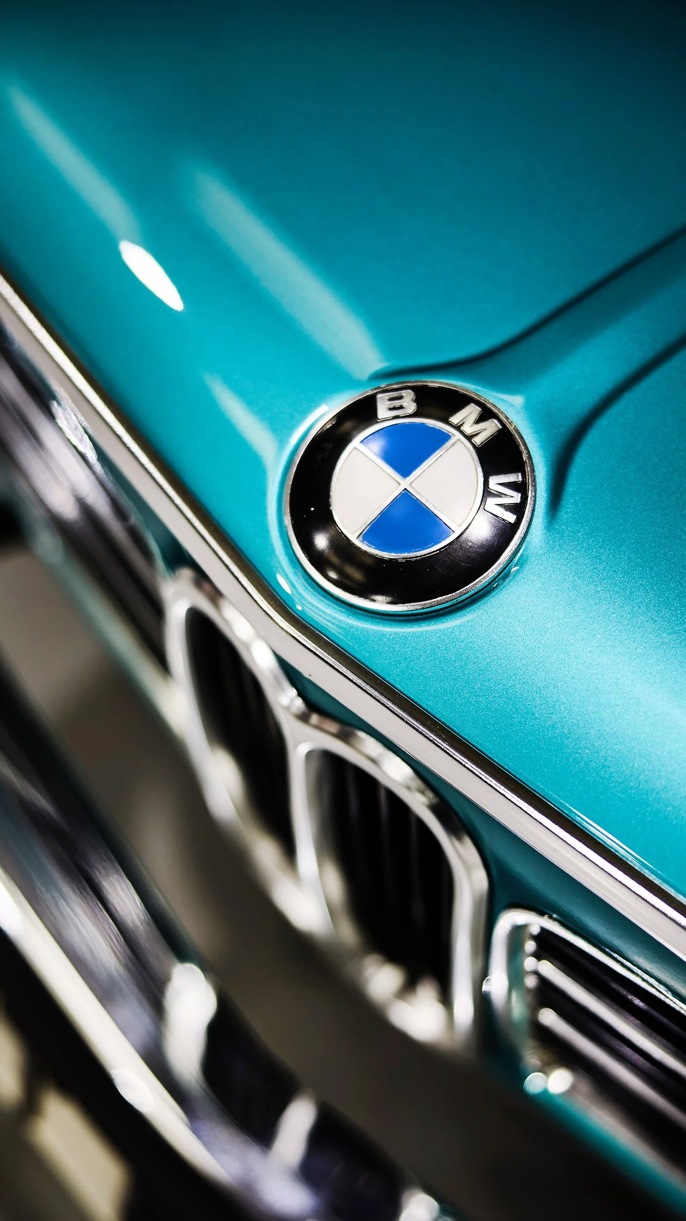 Close-up of a BMW emblem on a teal-colored vintage car.