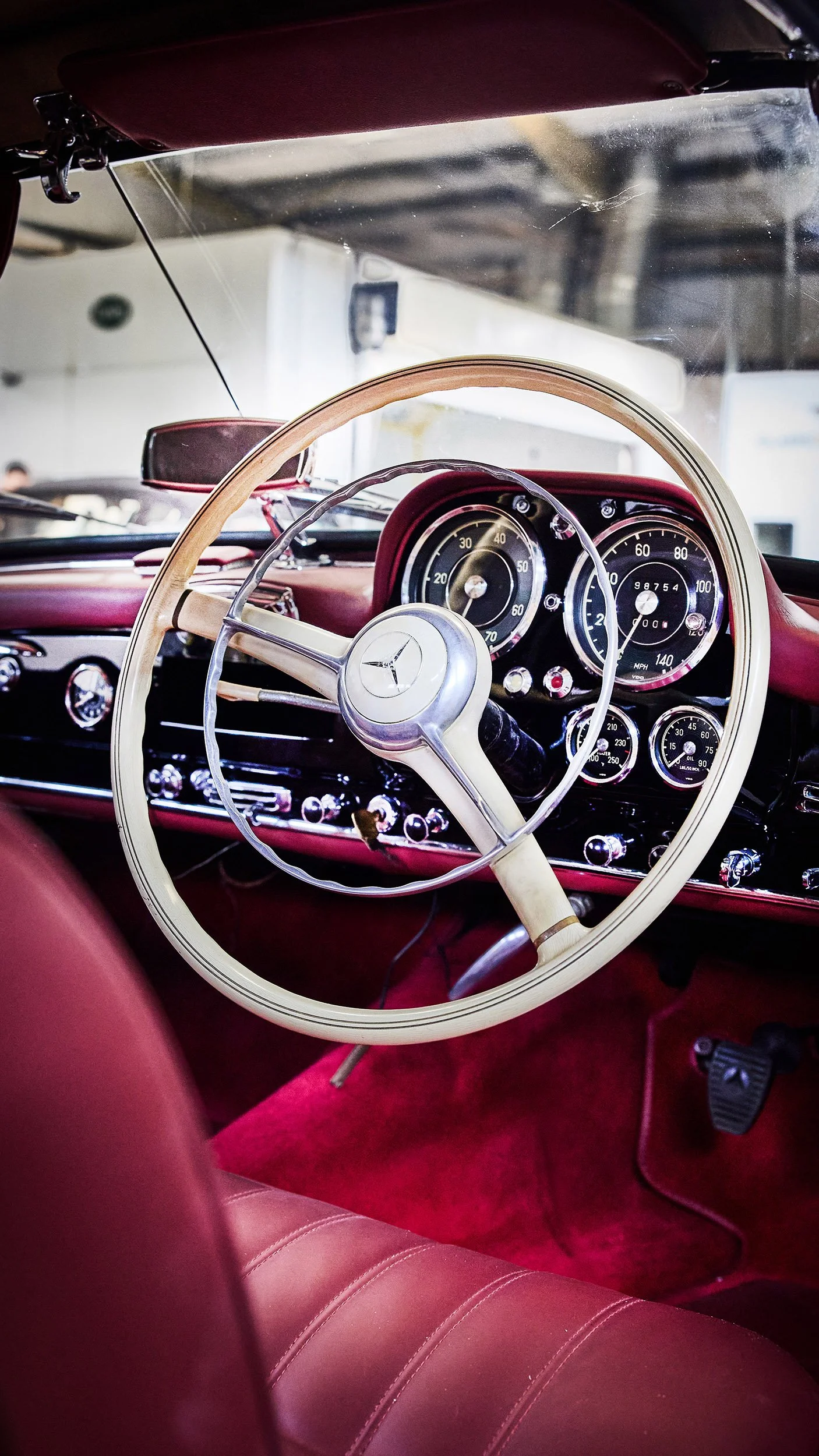 Inside view of a vintage Mercedes-Benz car showing the dashboard, steering wheel, and red leather interior.