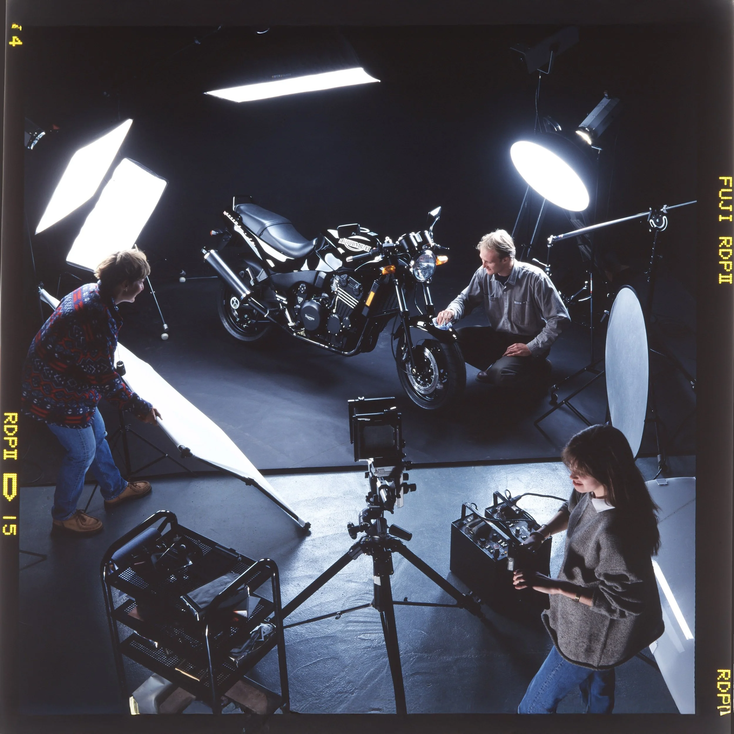 Charles Ward Photograph's team working in the studio photographing a motorcycle with professional flash equipment and film cameras.
