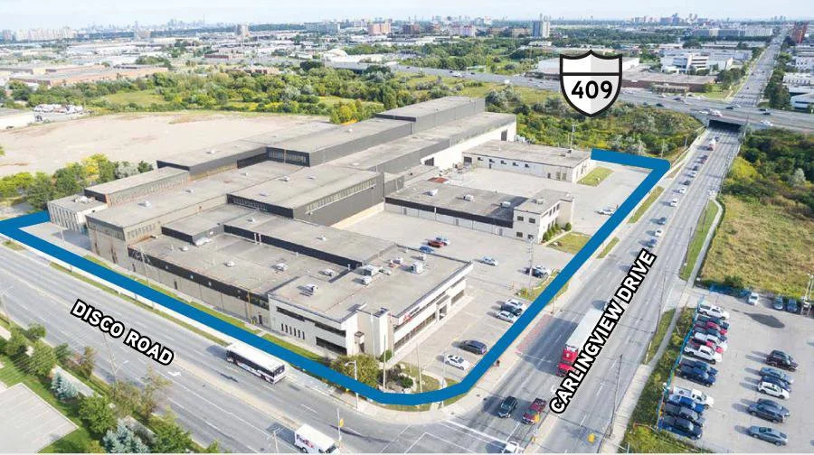 Aerial view of a large industrial or warehouse complex bordered by Disco Road and Garlington Drive, with visible parking lots and surrounding greenery, highway 409 nearby in an urban area.