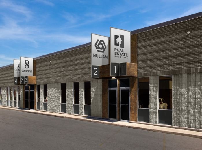 Commercial building with signs for different businesses or offices, numbered 1 to 4, under clear blue sky.