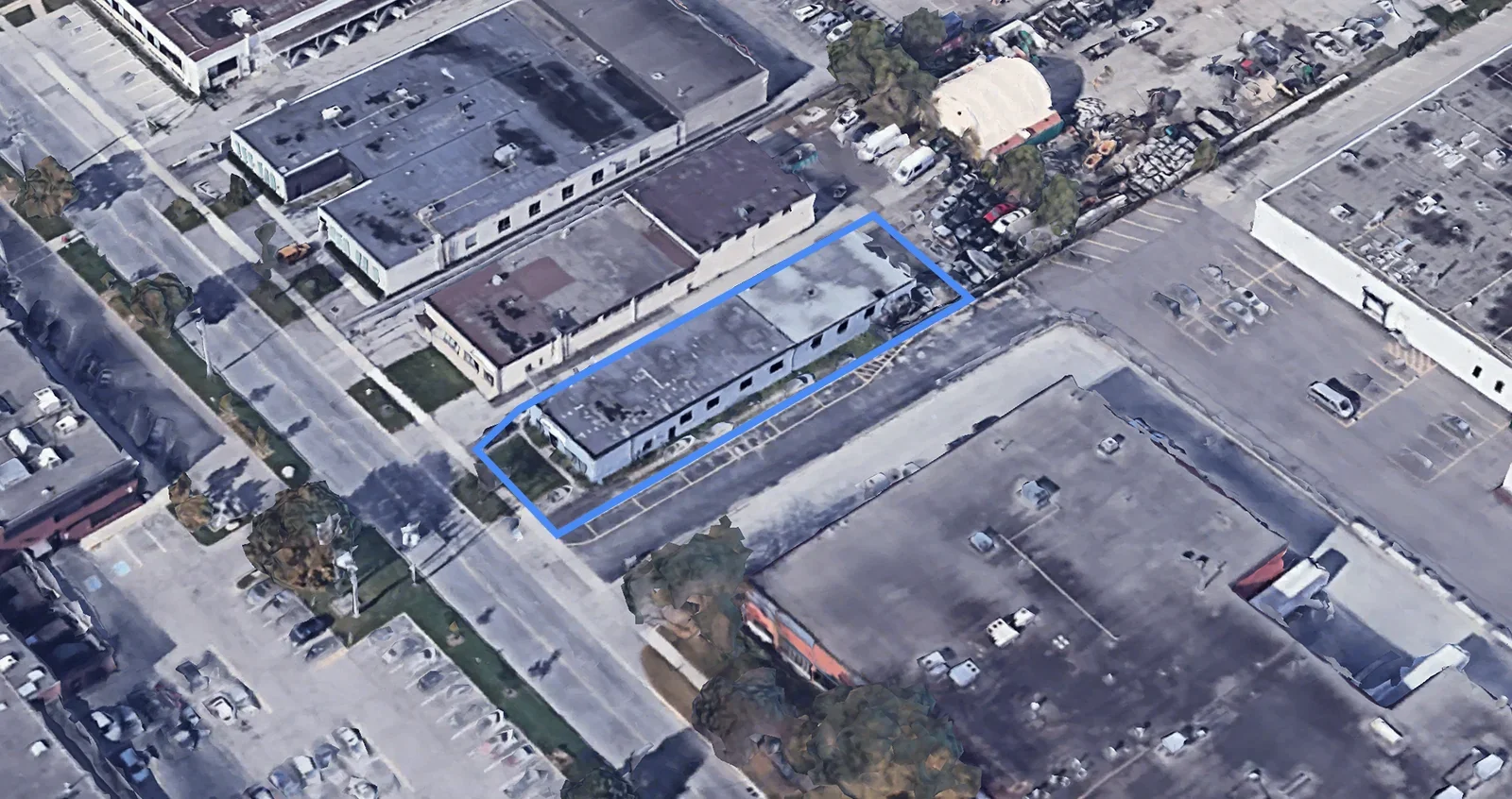 Aerial view of a commercial area showing parking lots, surrounding buildings, and a smaller outlined section in blue around one building.