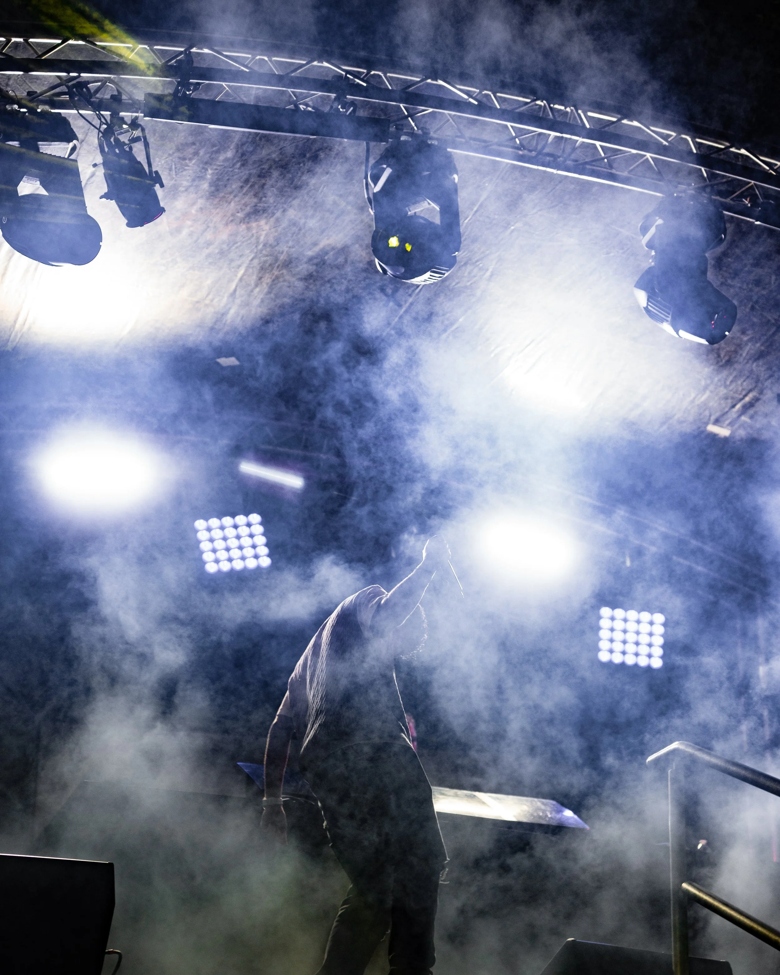 Silhouette of a performer on stage with bright lights and smoke