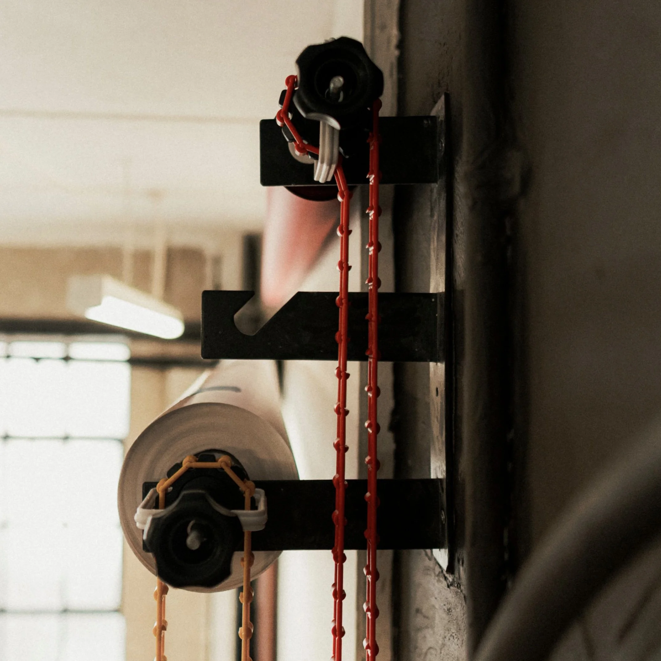 Close-up of a sprinkler system with red and orange tubes attached to black connectors on a wall.