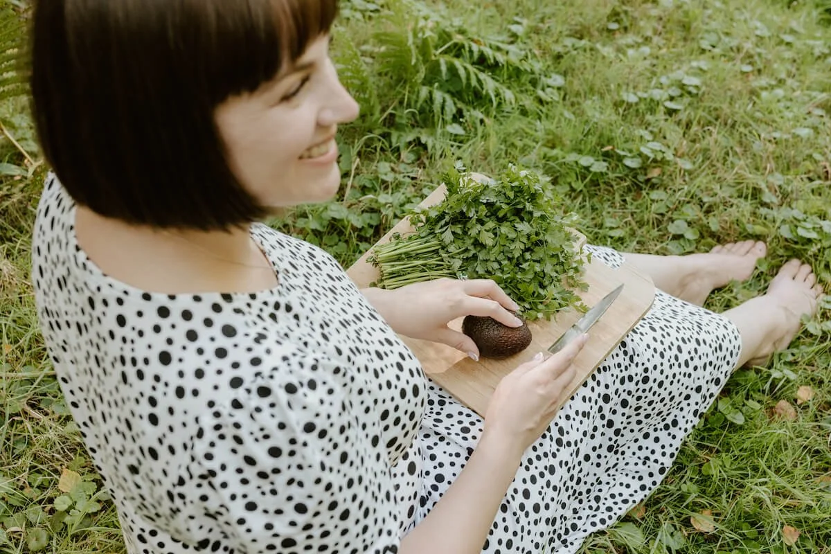 A woman smiling cutting an avocado
