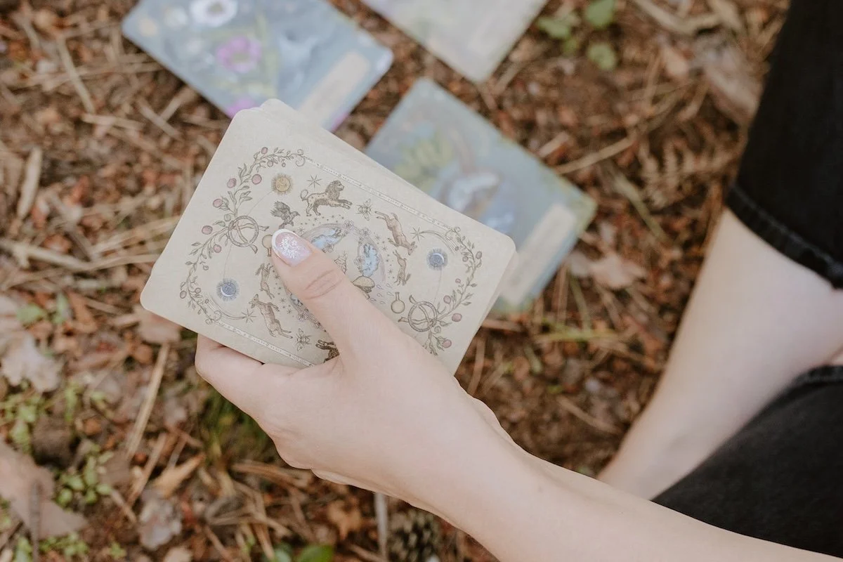 A hand holding a deck of oracle cards