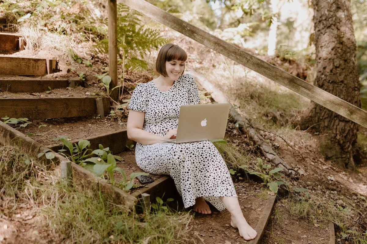 A woman sitting at a laptop in the woods