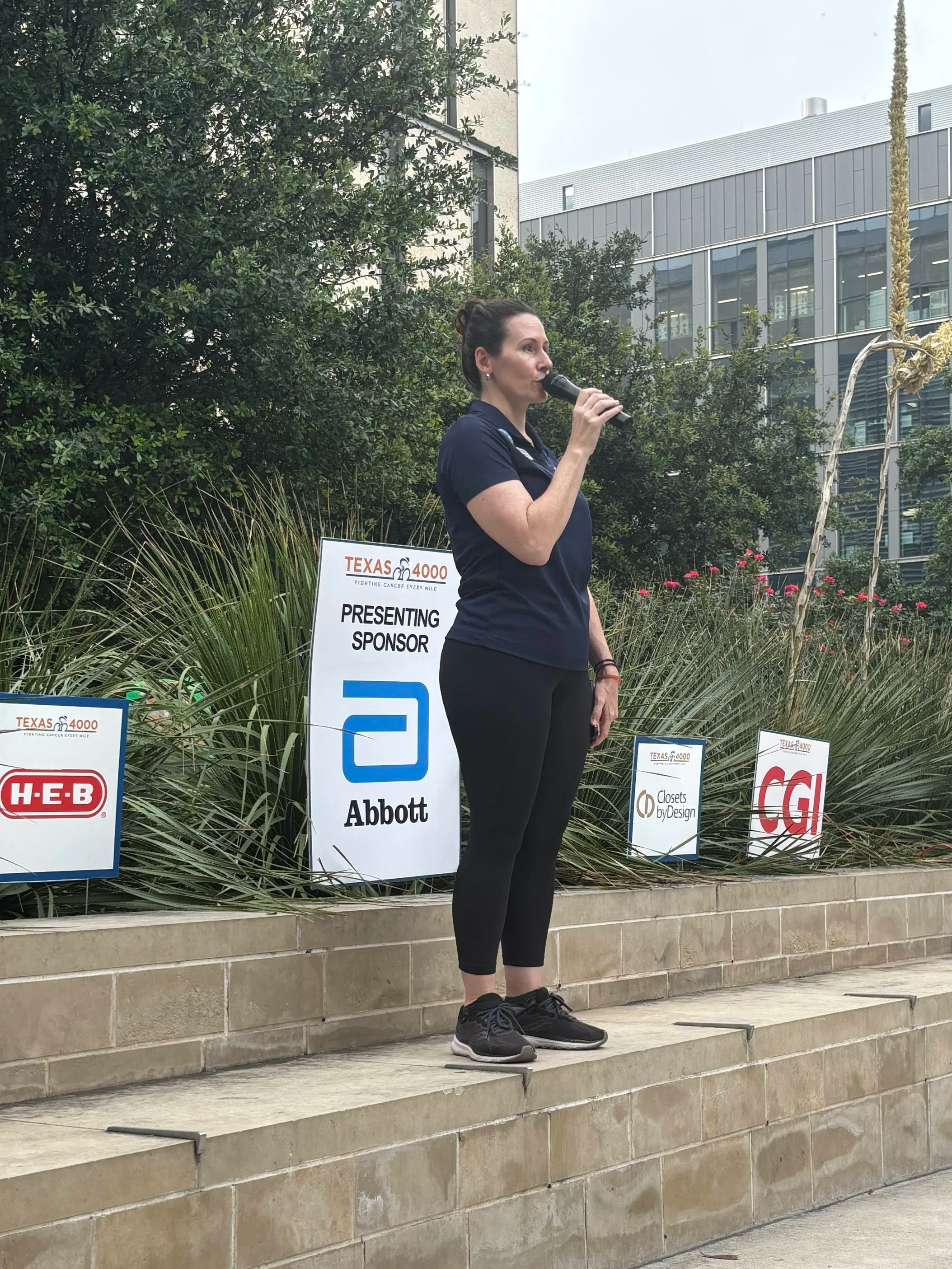 Bev speaking outdoors on a microphone, at UT Austin event