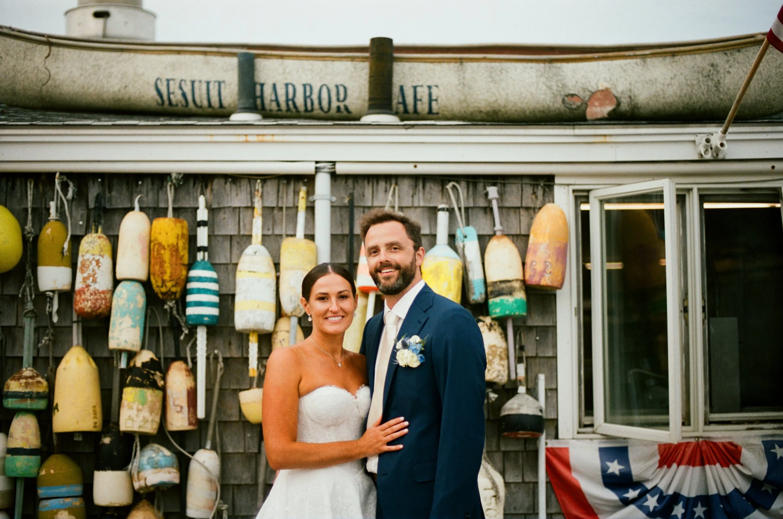 Film wedding photo from Cape Cod late summer coastal wedding. Couple portraits in front of boathouse in new england