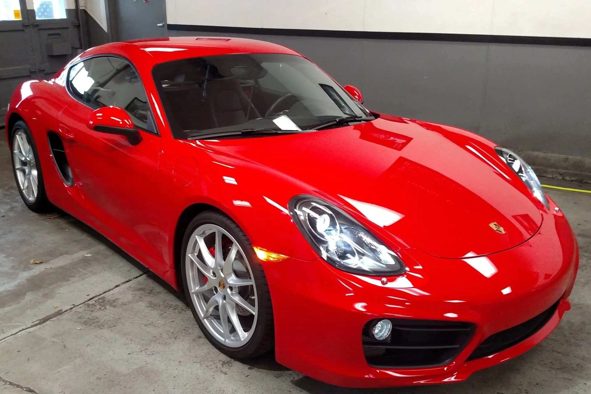 Red Porsche sports car parked in an indoor garage