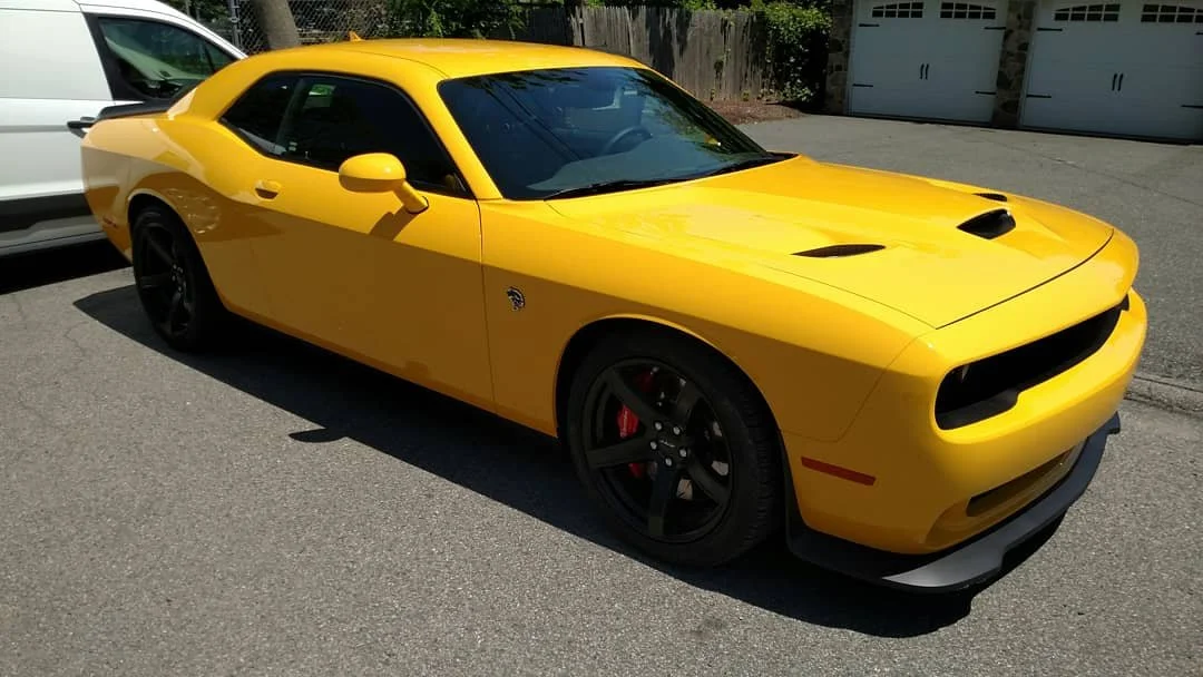 Yellow Dodge Challenger parked in a driveway.