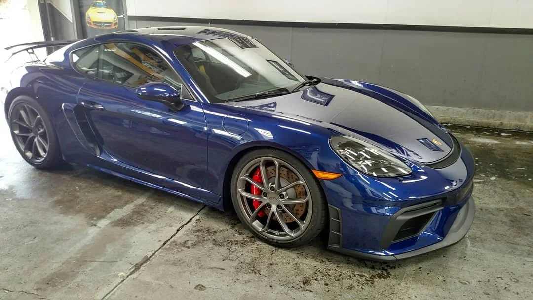 A blue sports car with black accents parked inside a garage.