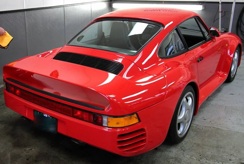 Red vintage Porsche 959 sports car inside a garage.