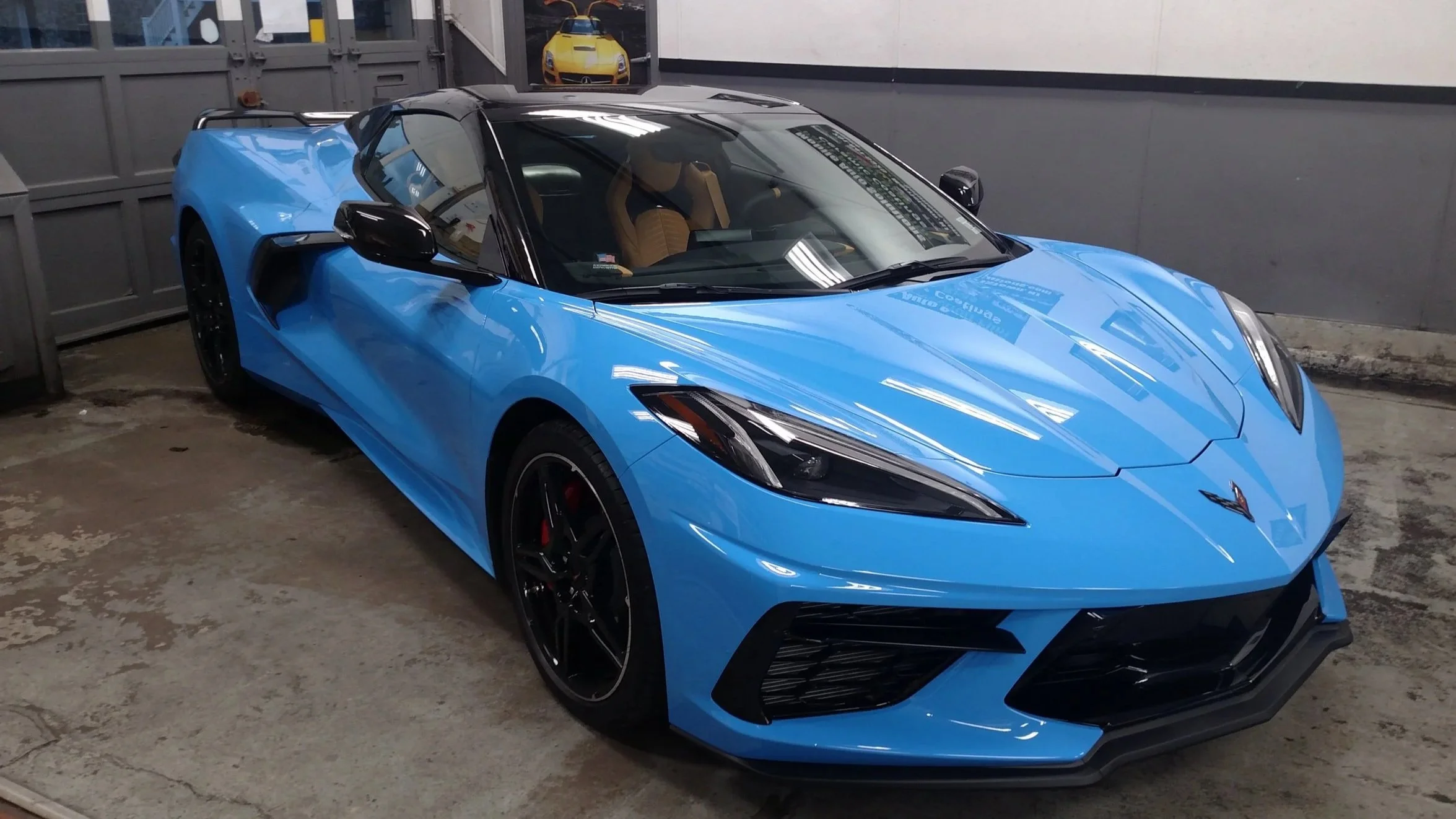 Blue Chevrolet Corvette sports car with black accents parked in a garage.