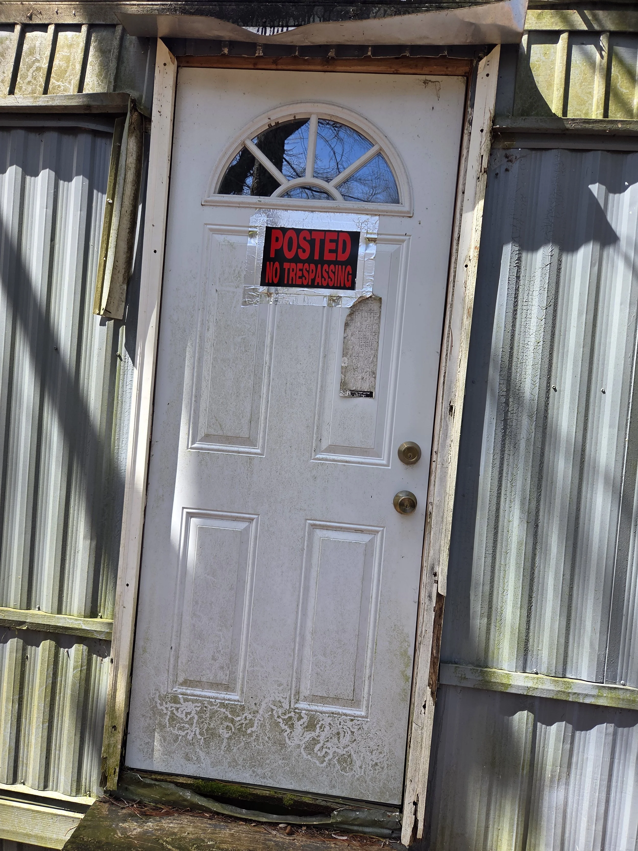 Close-up of a an improperly installed and shieled door. Rot is present on both sides of the door with top exterior trim missing.