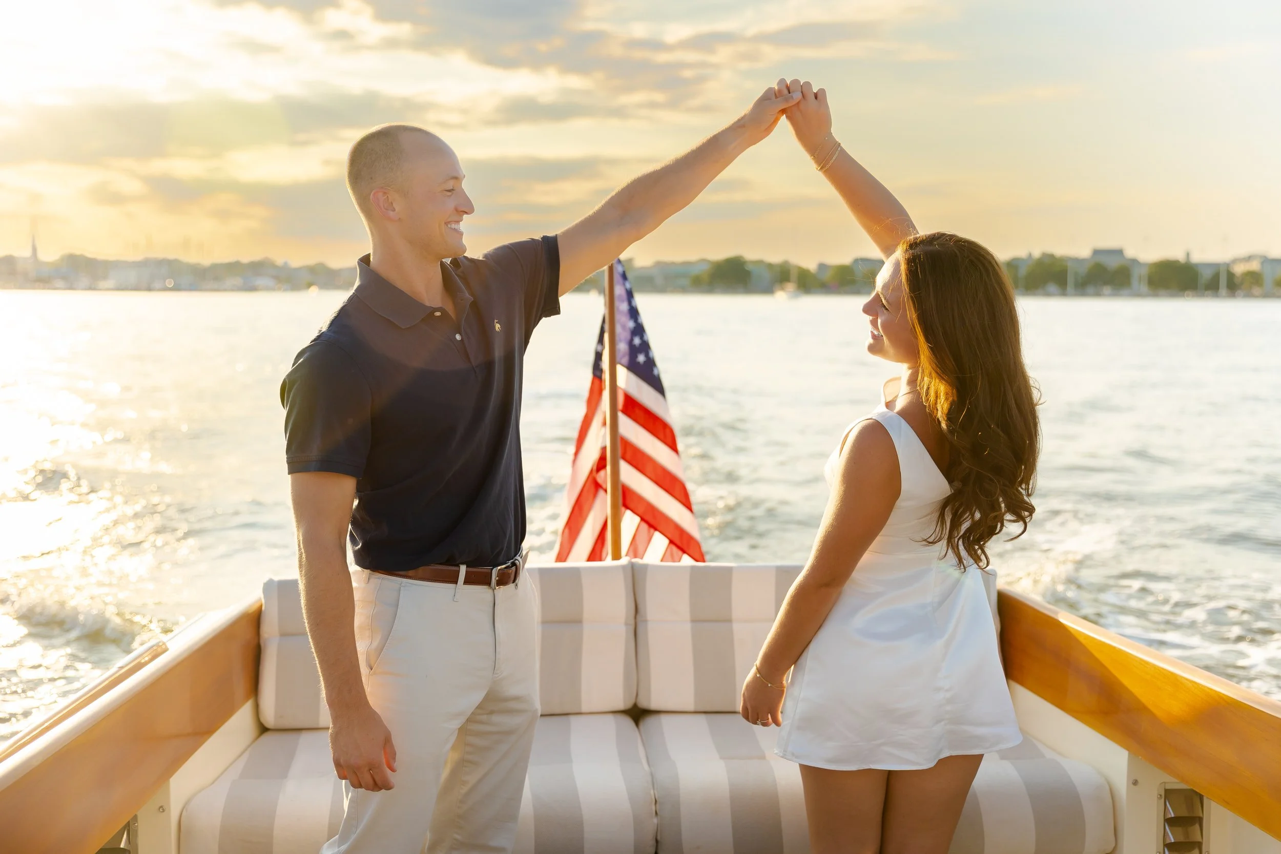 A couple taking engagement photos at sunset aboard Chesapeake Classic Yacht Charters' Hinckley Picnic Boat.  Stephanie Wyvill Photography