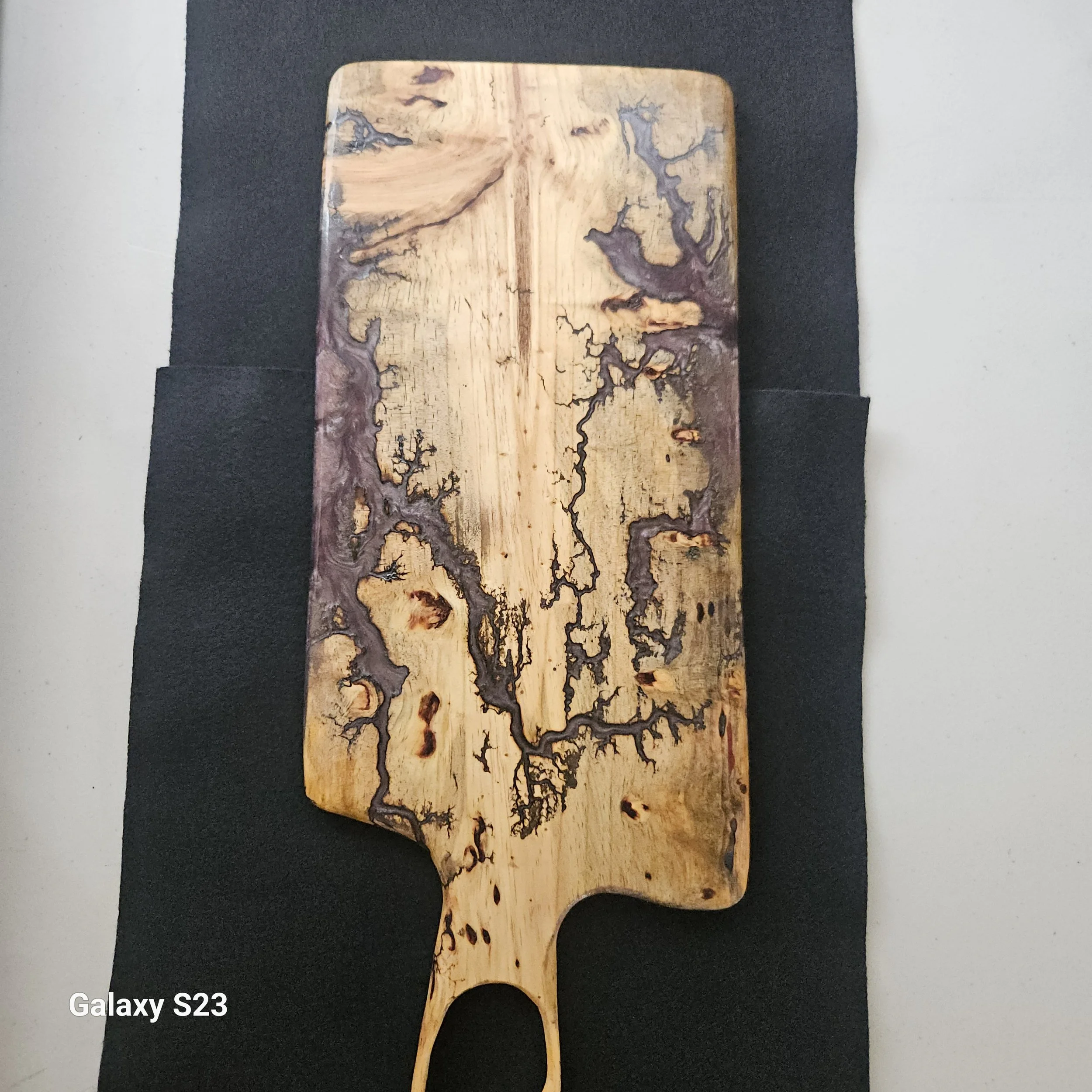 Wooden cutting board with intricate burnt patterns on a dark background