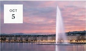 Water fountain spray at sunset with city skyline in the background, and a small date label in the top corner reading 'OCT 5'.