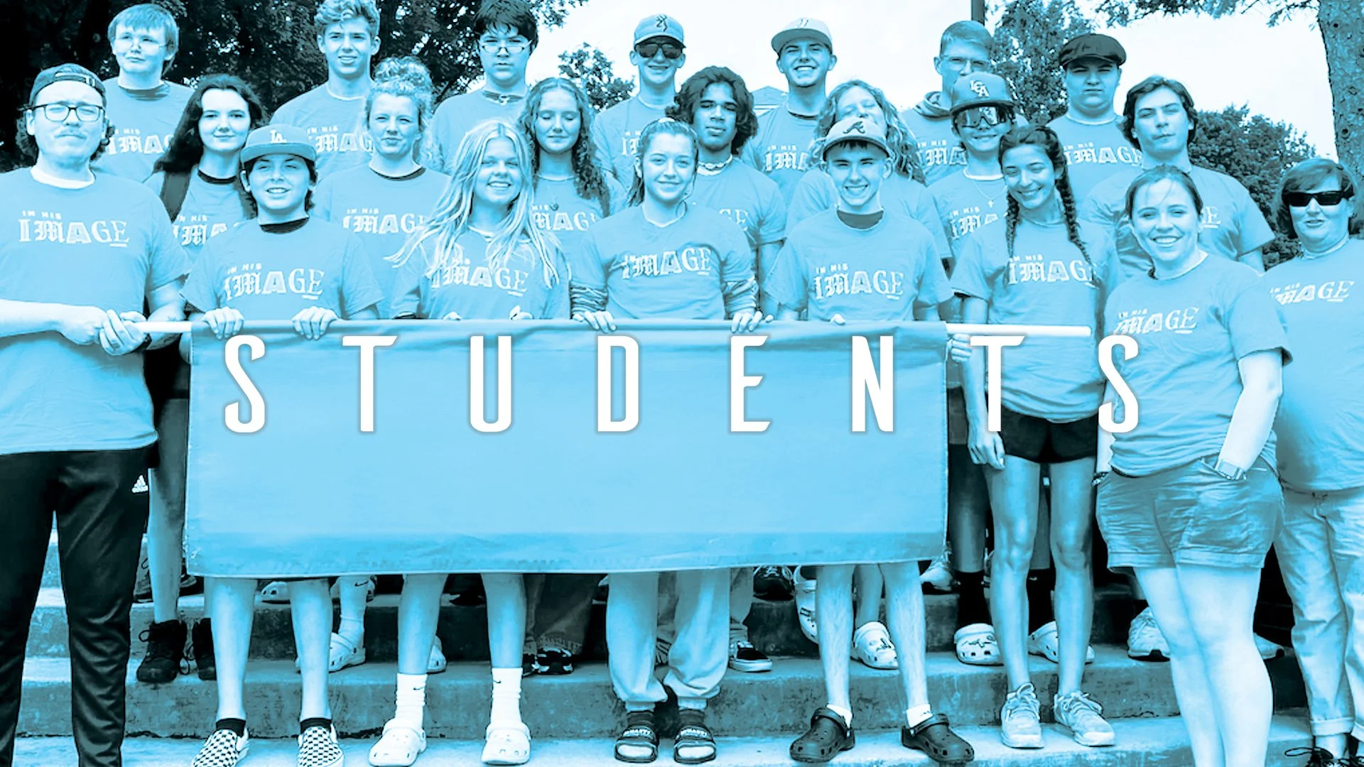 Group of students and adults posing outdoors, holding a banner that says 'STUDENTS', all wearing matching T-shirts with 'I'M AN IMAGE' printed on them.
