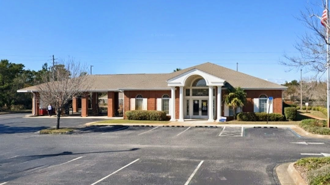 Exterior of Santa Rosa County Federal Credit Union Midway Branch on Gulf Breeze Parkway in Gulf Breeze, FL, a brick building with white columns, arched entryway, and parking lot.