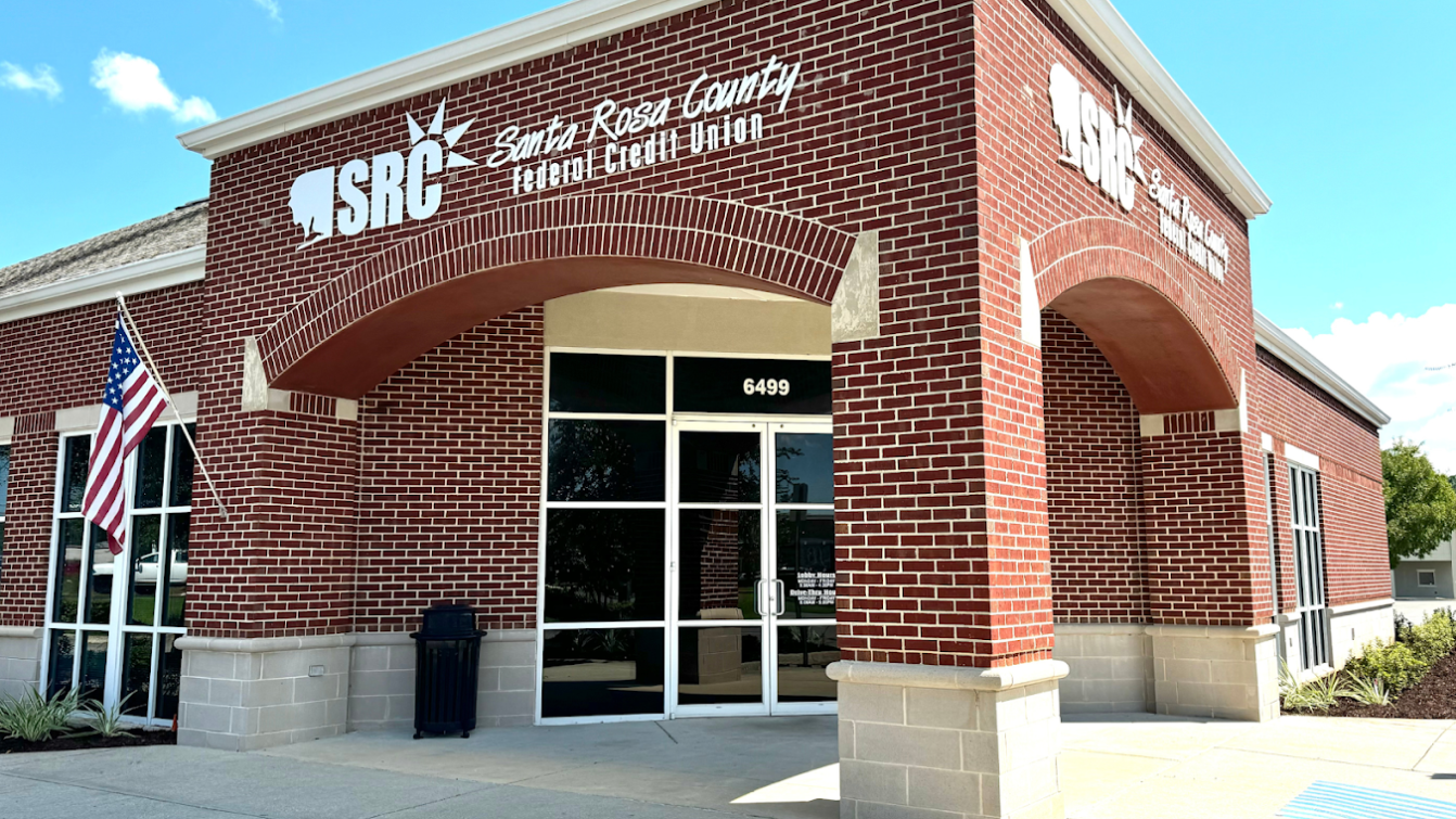 Exterior of Santa Rosa County Federal Credit Union Milton Branch at 6499 Caroline Street in Milton, FL, a brick building with arched entryway and American flag.