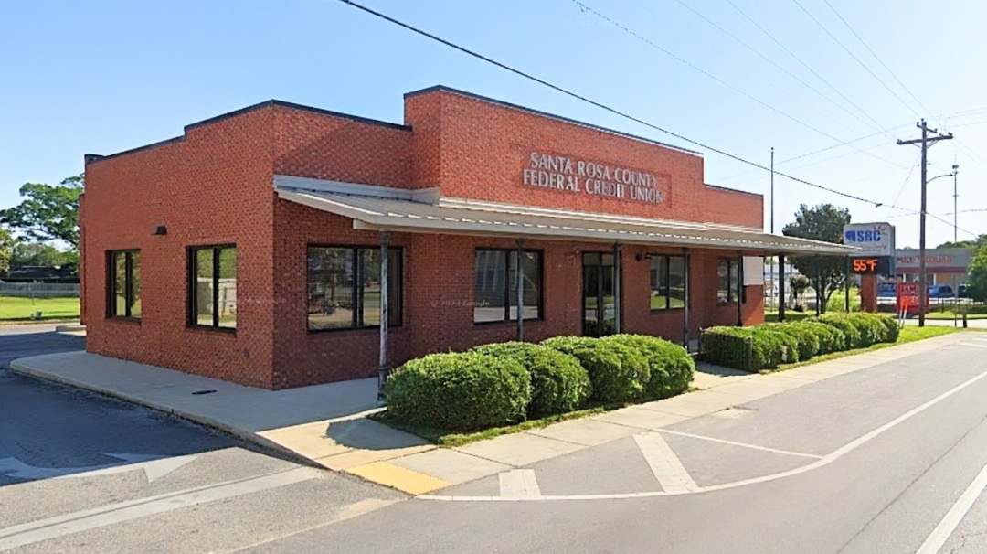 Santa Rosa County Federal Credit Union brick building exterior in Jay, Florida, with clear blue sky, sidewalk, and trimmed bushes along the front entrance.