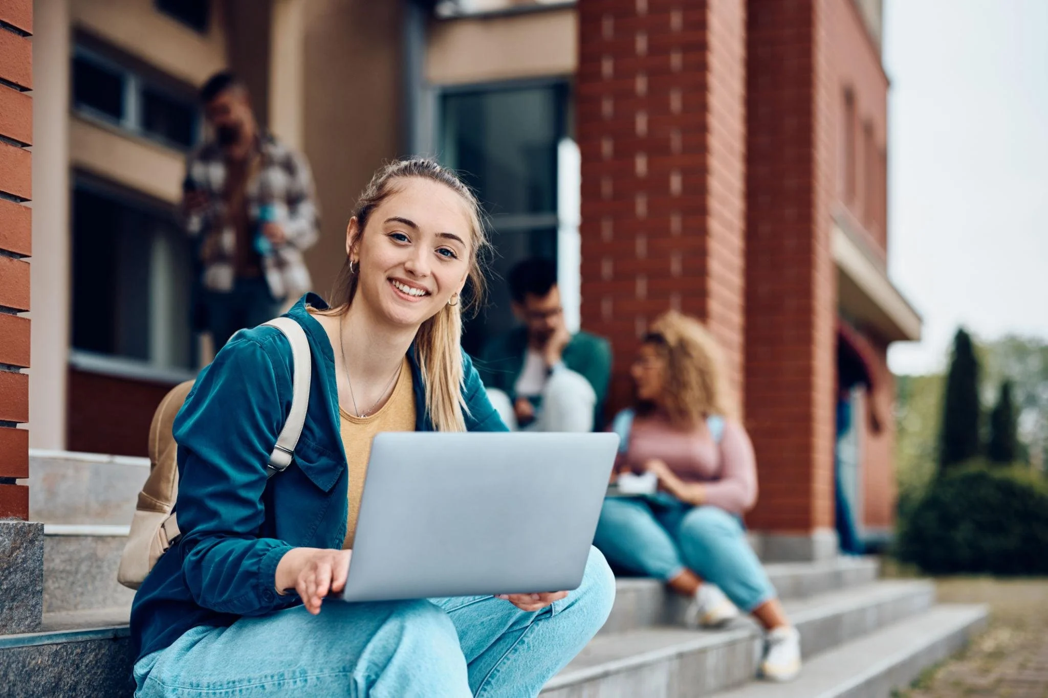 college student sitting on steps of school