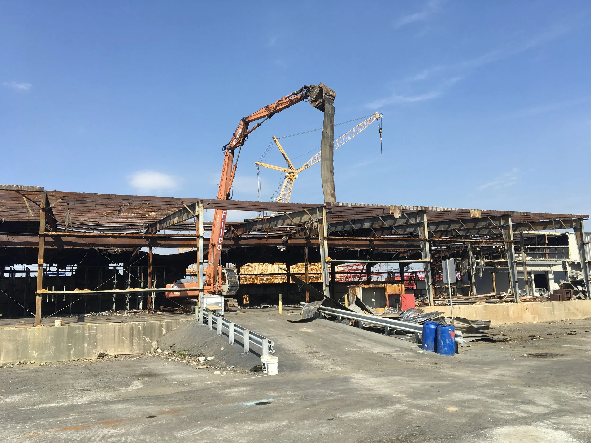 Burned-down building under renovation with construction cranes in the background, blue sky