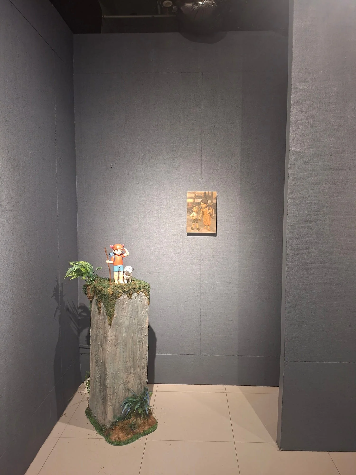 a corner view of a two front teeth resin sculpture and a painting of Gino