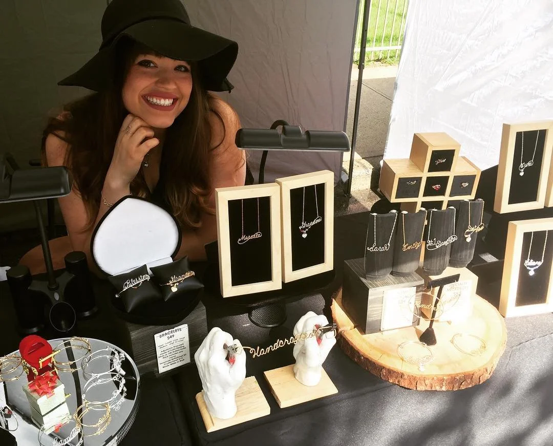 Ali Young of a multigenerational handcrafted wire jewelry family business, presenting personalized wire jewelry at the store display.